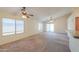 Open-concept living room with neutral carpet, two ceiling fans, and sliding glass doors to the patio at 1336 E Laurel Pl, Casa Grande, AZ 85122
