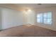 Bright living room featuring neutral carpet, a white interior door, and a large window with blinds at 1336 E Laurel Pl, Casa Grande, AZ 85122