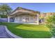 An inviting backyard features a covered patio, outdoor kitchen, synthetic grass, and mature trees at 1409 E Goldenrod St, Phoenix, AZ 85048