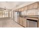 Well-lit kitchen with a white refrigerator and dishwasher with tan countertops and tile floor at 15011 W Verde Ln, Goodyear, AZ 85395