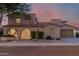 Twilight view of a two-story home featuring an arched entryway, well manicured yard, and a two-car garage at 16178 W Granada Rd, Goodyear, AZ 85395