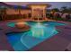Stunning pool with a fire feature, fountain, and lush landscaping at twilight at 16178 W Granada Rd, Goodyear, AZ 85395