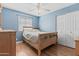 A cozy bedroom with a wooden bed frame, ceiling fan, and natural light from the window at 190 E Tremaine Ave, Gilbert, AZ 85234