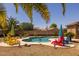 Beautiful backyard pool surrounded by colorful chairs, lush landscaping, and sunny skies at 2990 N Pearl Ct, Casa Grande, AZ 85122