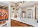 Bathroom with a wood vanity, white countertop, decorative mirror, and desert-themed shower curtain for added charm at 38771 N Dena Dr, San Tan Valley, AZ 85140