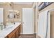 Neutral-toned bathroom featuring a wood vanity, white countertop, decorative mirror, and white door at 38771 N Dena Dr, San Tan Valley, AZ 85140