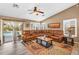Spacious living room featuring a large leather sectional, wood-look floors, shutters, and a sliding door to the pool at 38771 N Dena Dr, San Tan Valley, AZ 85140