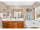 Bright main bathroom with dual sinks, soaking tub, decorative wall art, and ample lighting at 38771 N Dena Dr, San Tan Valley, AZ 85140