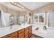 Well-lit main bathroom with dual sinks, a soaking tub, a separate shower, and a window at 38771 N Dena Dr, San Tan Valley, AZ 85140