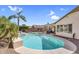 Inviting backyard oasis with a sparkling pool, palm trees, and lounge area, perfect for outdoor relaxation at 38771 N Dena Dr, San Tan Valley, AZ 85140