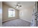 Cozy bedroom with large window, ceiling fan, and plush carpeting, providing a relaxing space at 3897 E Douglas Loop, Gilbert, AZ 85234
