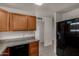 Kitchen with wooden cabinets, granite countertops, and a modern black refrigerator at 4644 W Havasupai Dr, Glendale, AZ 85308