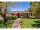 Charming home featuring lush green lawn, red brick walkway, and inviting front porch with red umbrella and door at 4710 N 33Rd Pl, Phoenix, AZ 85018