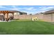 Large backyard with manicured artificial grass, complemented by a pergola, dining set, and play area at 5650 S Feliz --, Mesa, AZ 85212