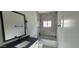 Modern bathroom featuring gray tile, black fixtures, and a bathtub with a shower for a clean and functional design at 7724 E Charter Oak Rd, Scottsdale, AZ 85260