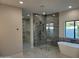 Modern bathroom featuring a glass-enclosed shower with gray tile and a freestanding white bathtub at 7724 E Charter Oak Rd, Scottsdale, AZ 85260