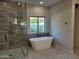 Elegant bathroom with a modern tub, glass-enclosed shower, and large window with natural light at 7724 E Charter Oak Rd, Scottsdale, AZ 85260
