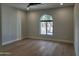 Bright bedroom with light hardwood floors and a large arched window overlooking lush greenery for a serene living space at 7724 E Charter Oak Rd, Scottsdale, AZ 85260