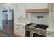 Stainless steel refrigerator and a range featuring white cabinets and marble backsplash at 7724 E Charter Oak Rd, Scottsdale, AZ 85260