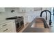 Modern island with a sink, black faucet, range, and white cabinetry at 7724 E Charter Oak Rd, Scottsdale, AZ 85260