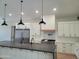 Modern kitchen featuring a large island, stainless steel appliances, and stylish pendant lighting at 7724 E Charter Oak Rd, Scottsdale, AZ 85260