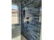 Modern shower with blue tiled walls, a rainfall showerhead, and black fixtures, providing a luxurious bathing experience at 7724 E Charter Oak Rd, Scottsdale, AZ 85260