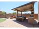 Under a covered patio, this outdoor kitchen features a built-in grill, bar seating, and ample counter space at 9337 W Medlock Dr, Glendale, AZ 85305
