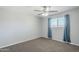 Neutral bedroom featuring a ceiling fan, window with blue curtains, and plush carpet flooring at 1066 E 7Th Pl, Mesa, AZ 85203