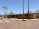 Exterior shot of a single-story brick house with palm trees, desert landscaping, and a gravel driveway at 11041 N Hayden Rd, Scottsdale, AZ 85260