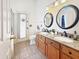 Bathroom with dual sinks, granite counters, and a door to the backyard at 12770 W Alvarado Rd, Avondale, AZ 85392