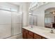 Clean bathroom featuring a double vanity, large mirror, and a glass-enclosed shower for added convenience at 14821 W Honeysuckle Ln, Surprise, AZ 85374