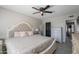 Comfortable bedroom featuring a tufted headboard, ceiling fan, and white dresser. Wood-look tile floor at 17634 N 34Th Ln, Phoenix, AZ 85053