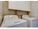 Functional laundry room equipped with a washer, dryer, and overhead storage cabinets for convenience at 18130 N 92Nd Ln, Peoria, AZ 85382