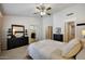 Spacious main bedroom featuring a ceiling fan, dresser, and a well-lit doorway to the ensuite bathroom at 18130 N 92Nd Ln, Peoria, AZ 85382