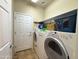 Practical laundry room with washer, dryer, shelving, and a utility door to the outside at 26243 W Wahalla Ln, Buckeye, AZ 85396