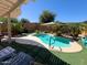 Relaxing backyard oasis with a sparkling pool, lush greenery, and comfortable lounge area at 26243 W Wahalla Ln, Buckeye, AZ 85396