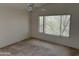 Empty bedroom with a large window providing a view of foliage and carpeted floors at 3428 E Renee Dr, Phoenix, AZ 85050