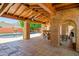 Charming covered patio featuring a fireplace, brick columns, and outdoor seating area near a pool at 5112 N 32Nd Pl, Phoenix, AZ 85018