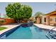 Backyard pool surrounded by mature trees, a covered patio, and an outdoor cooking area at 5112 N 32Nd Pl, Phoenix, AZ 85018
