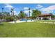 Expansive backyard featuring a lush artificial lawn, swimming pool, covered patio, and mature landscaping for private outdoor living at 5320 W Soft Wind Dr, Glendale, AZ 85310
