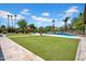Manicured backyard with artificial grass, swimming pool, and lush landscaping at 5320 W Soft Wind Dr, Glendale, AZ 85310