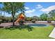 A verdant backyard with a play structure, trampoline, and lush landscaping invites outdoor fun and relaxation at 5320 W Soft Wind Dr, Glendale, AZ 85310