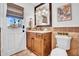Bathroom featuring travertine tile, wooden vanity, granite countertop, and decorative mirror at 5320 W Soft Wind Dr, Glendale, AZ 85310