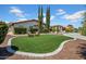 Charming front yard featuring a grassy area, desert landscaping, and mature trees at 5320 W Soft Wind Dr, Glendale, AZ 85310