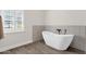 Freestanding bathtub beside a window with natural light and gray tile accents at 856 W Quail Cir, San Tan Valley, AZ 85143