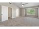 Open bedroom with neutral walls, ceiling fan, vaulted ceiling, and view of backyard from window at 1073 N 159Th Dr, Goodyear, AZ 85338