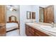 A bathroom with a double vanity, travertine countertops, wood cabinets, and a separate bedroom entrance at 11307 E Elmhurst Dr, Chandler, AZ 85249