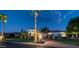 Stately home exterior at dusk with palm trees, lush lawn, illuminated driveway, and distinctive architecture at 11307 E Elmhurst Dr, Chandler, AZ 85249
