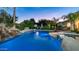 Beautiful pool with rock waterfall feature, lush landscaping, basketball hoop, and night lighting at 11307 E Elmhurst Dr, Chandler, AZ 85249