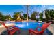 Inviting pool with rock waterfall, palm trees, and comfortable red lounge chairs at 11307 E Elmhurst Dr, Chandler, AZ 85249